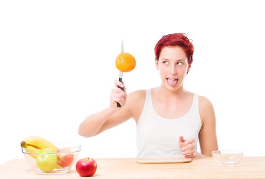 Young woman with knife has fun with an orange on a white background