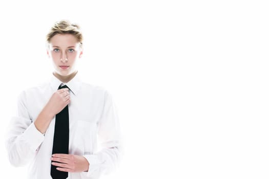 Young androgynous woman straightens her tie on a white background