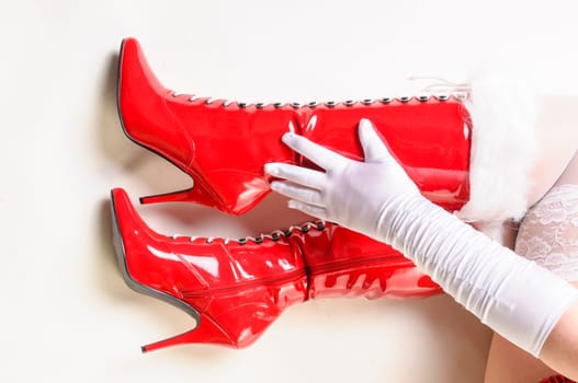 Close-up of red boots with a white fur collar and a hand with white gloves.