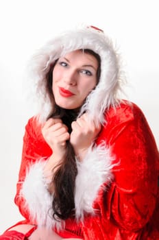 Adult overweight woman with long dark hair wears a red Christmas coat and covers her collar with both hands,exposed against a white background.