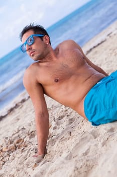 Sporty young man in swimming trunks on the beach on holiday summer leisure lifestyle