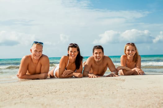 Group of laughing young people on the beach in summer holiday leisure lifestyle