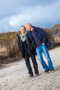 Older adult happy couple walking on the beach in autumn lifestyle happiness