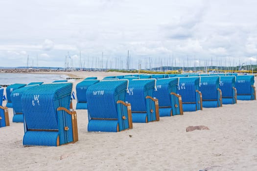 blue beach chairs in a row on sandy underground near kuehlungsborn, baltic sea, germany