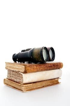 Antique books and binoculars symbolizing adventure and travel book, on a white background