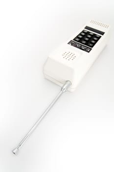 A white cordless telephone from the eigthes with black buttons and a telescopic antenna
