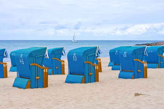 blue beach chairs in a row on sandy underground near kuehlungsborn, baltic sea, germany