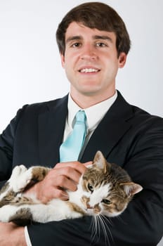Upper body portrait of a man in a black suit with a wiggling cat in his arms smiling into the camera