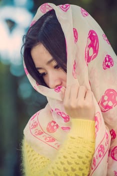 Beautiful young woman with skull covering head and face in sunshine
