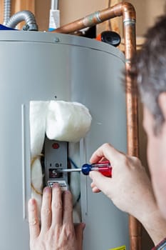 A technician is performing maintenance on a residential water heater
