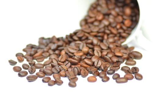 coffee beans scattered out of a cup isolated on white