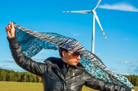 An image of girl holding canvas-cape and windturbine in background