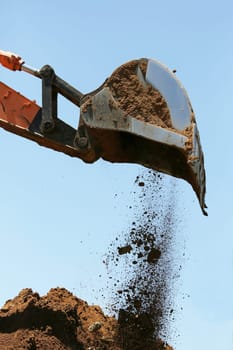 Industrial excavator machine scooping up sand and rocks