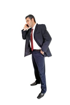 A tall handsome businessman standing for white background in a blue .suit and red tie talking on his cell phone..