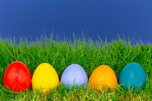 Colourful Easter eggs in a row on a meadow