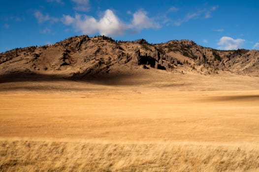Grassland leads up to rocky hillside in this northern rural landscape