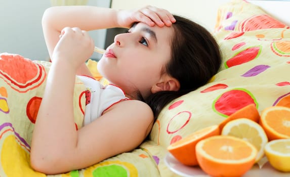 Little girl with a thermometer in bed