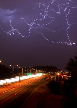 Batch of lightning over a busy highway at night