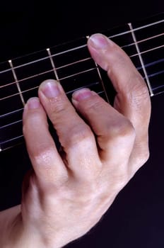 Close up of guitarist holding down a chord on the fretboard