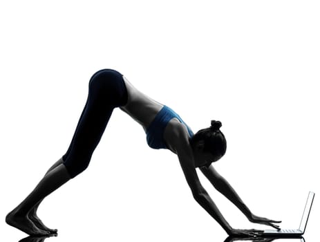 one caucasian woman exercising yoga using computer laptop in silhouette studio isolated on white background