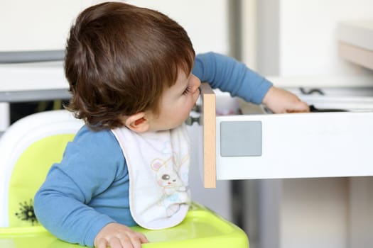 Details of a little boy who is trying to catch a knife in a drawer in kitchen.