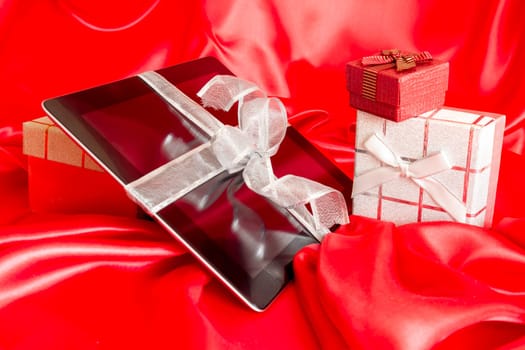 Digital tablet with christmas present on red background