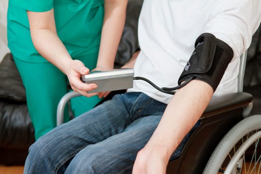 Blood pressure check for young adult in wheelchair.