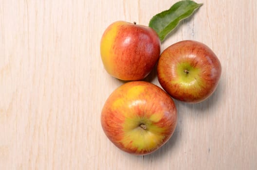 Three fresh apples on a wooden table with space for text