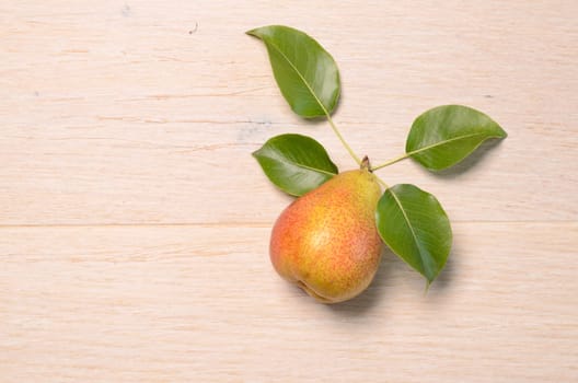 Fresh pear with leaves on a wooden background with space for text