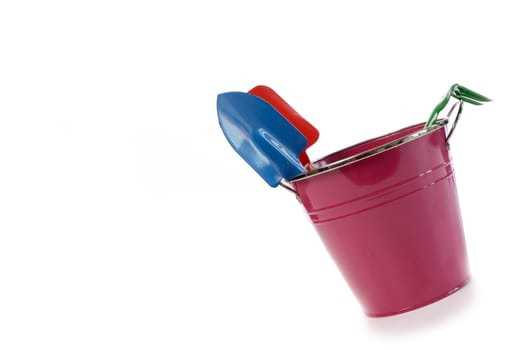 Gardening tools in a violet bucket on a white background