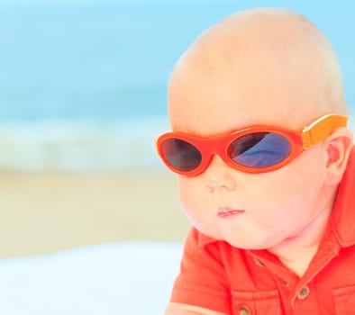 Cute baby wearing sunglasses on the sunbed