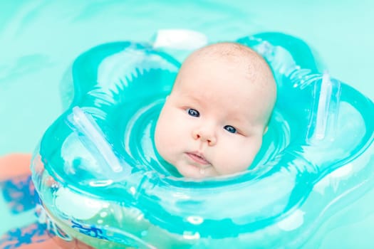 Baby swimming with neck swim ring in pool