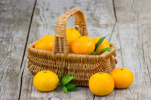 fresh tangerines in a basket on old wooden background