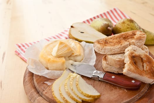 Caese,bread and fresh pears on cutting board
