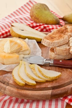 Caese,bread and fresh pears on cutting board