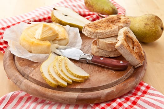 Caese,bread and fresh pears on cutting board