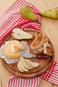 Caese,bread and fresh pears on cutting board