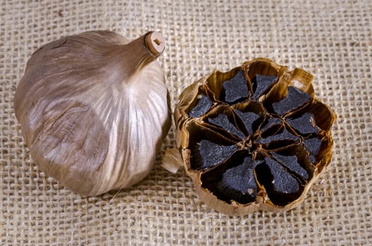 Black garlic bulb with cross section showing black cloves