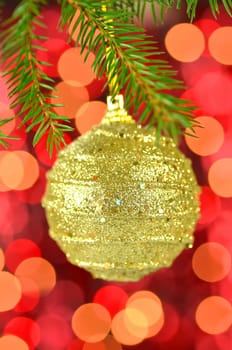 christmas decoration, golden Christmas ball hanging on spruce twig against bokeh background