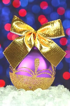 christmas decoration, violet Christmas ball with golden bow in bokeh background