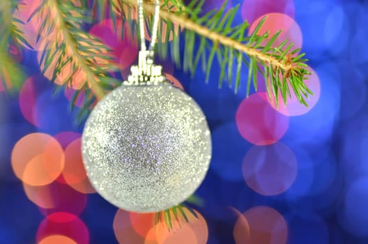 christmas decoration, golden Christmas ball hanging on spruce twig against bokeh background