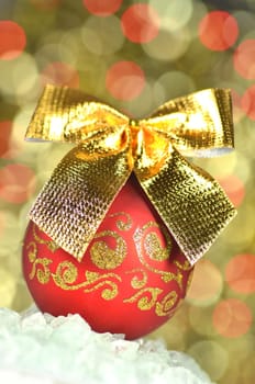 christmas decoration, red Christmas ball with golden bow in bokeh background