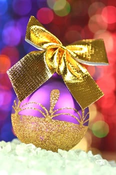 christmas decoration, violet Christmas ball with golden bow in bokeh background