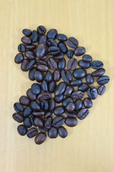 heart image made up of coffee beans on wood background