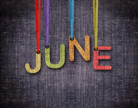 June letters hanging strings with blue sackcloth background.