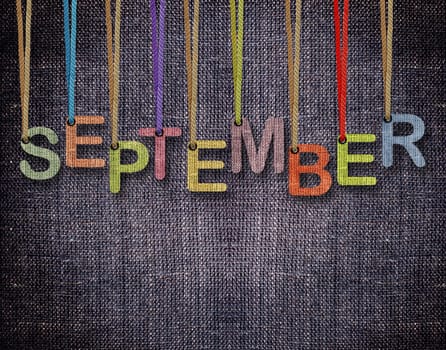 September letters hanging strings with blue sackcloth background.