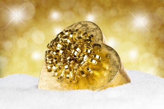 Golden gift on snow in front of a golden background