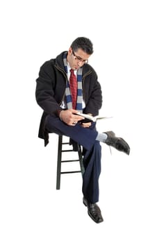 A young businessman with glasses sitting on a chair with a book in his hand.and reading, for white background..