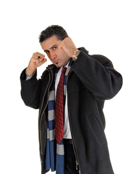 A young handsome man in a black coat standing for white background.with his fists up looking for a fight..