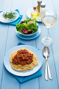 Spaghetti Bolognese with green salad and wine close up